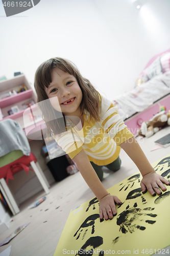 Image of cute little girl at home painting with hands