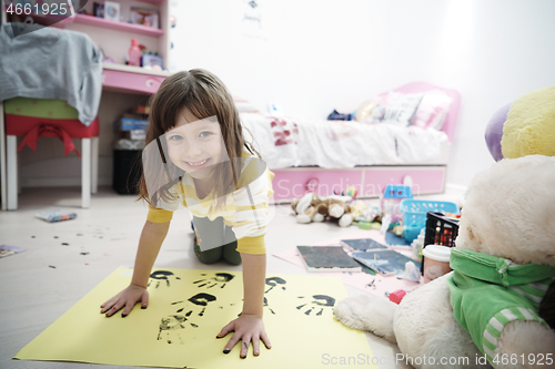 Image of cute little girl at home painting with hands