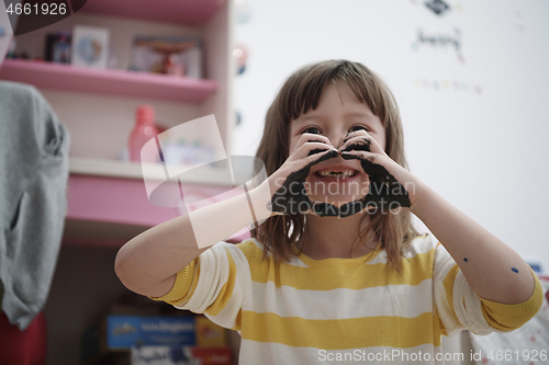 Image of cute little girl at home painting with hands