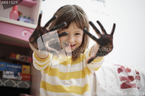 Image of cute little girl at home painting with hands