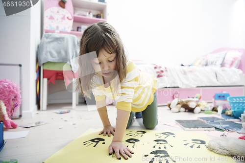 Image of cute little girl at home painting with hands