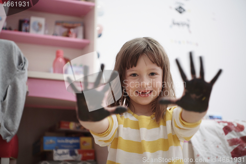 Image of cute little girl at home painting with hands