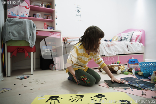 Image of cute little girl at home painting with hands