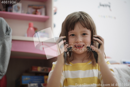 Image of cute little girl at home painting with hands