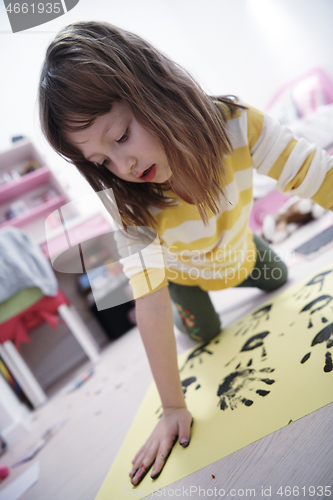 Image of cute little girl at home painting with hands