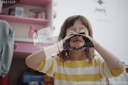 Image of cute little girl at home painting with hands