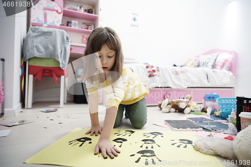 Image of cute little girl at home painting with hands