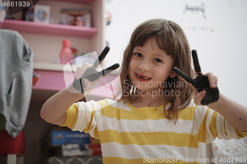 Image of cute little girl at home painting with hands