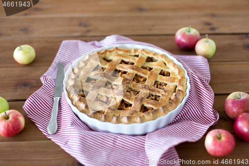 Image of close up of apple pie in baking mold and knife