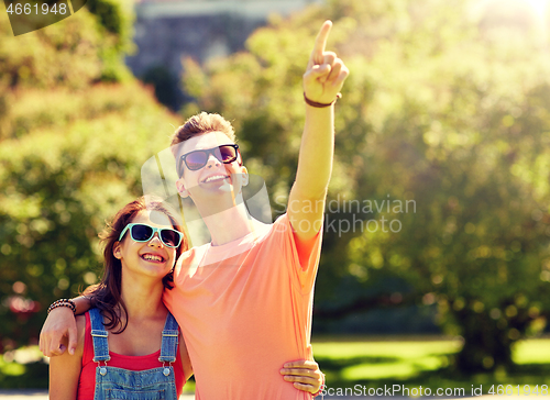 Image of happy couple pointing finger at summer park