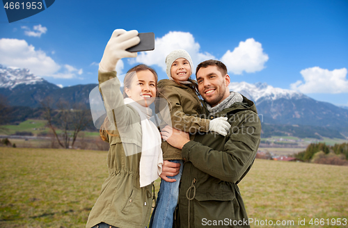 Image of family taking selfie by smartphone over alps