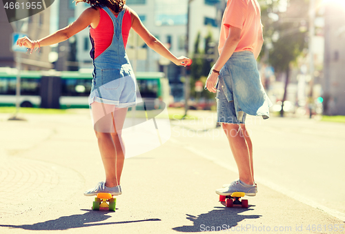 Image of teenage couple riding skateboards on city street