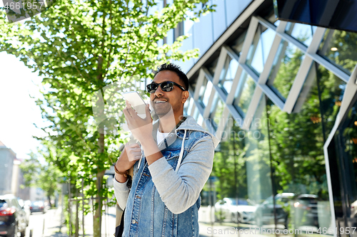 Image of man recorving voice message on smartphone in city