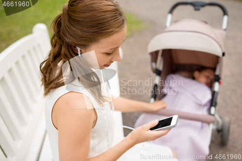 Image of mother with smartphone, earphones and stroller
