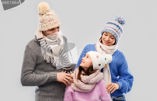 Image of happy family in winter clothes on grey background