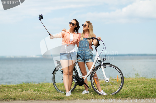 Image of teenage girls with bicycle taking selfie in summer