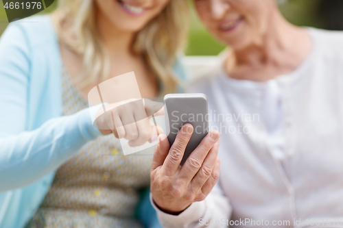 Image of daughter and senior mother with smartphone at park