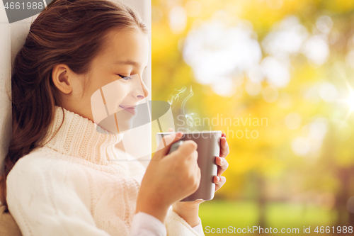 Image of girl with tea mug sitting at home window in autumn