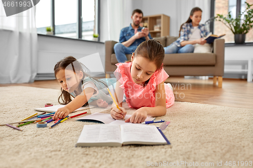 Image of happy sisters drawing and doing homework at home