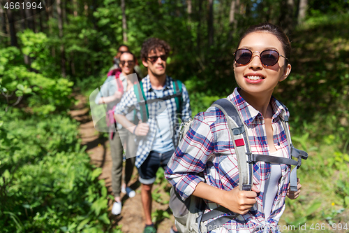 Image of group of friends with backpacks hiking in forest