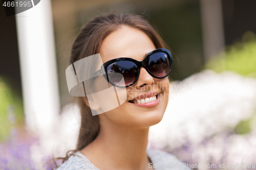 Image of happy young woman in sunglasses at summer garden