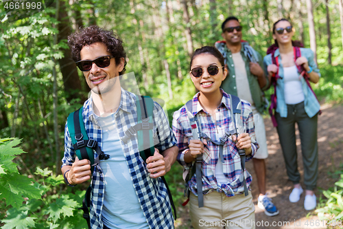 Image of group of friends with backpacks hiking in forest