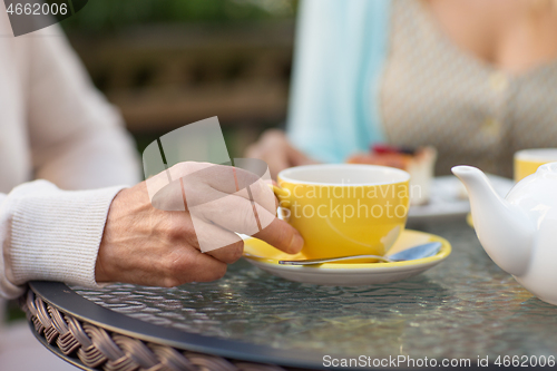 Image of hand of senior woman drinking tea at outdoor cafe