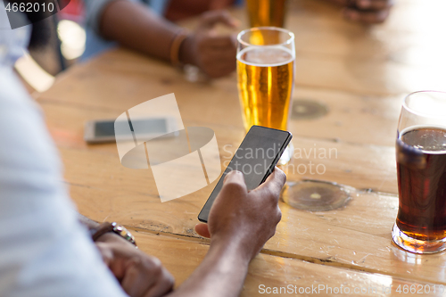 Image of man with smartphone drinking beer at bar or pub