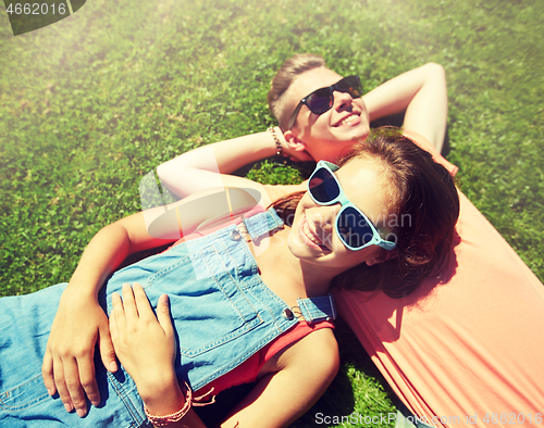 Image of happy teenage couple lying on grass at summer