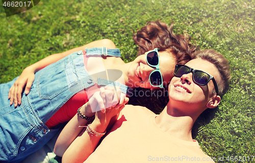 Image of happy teenage couple lying on grass at summer