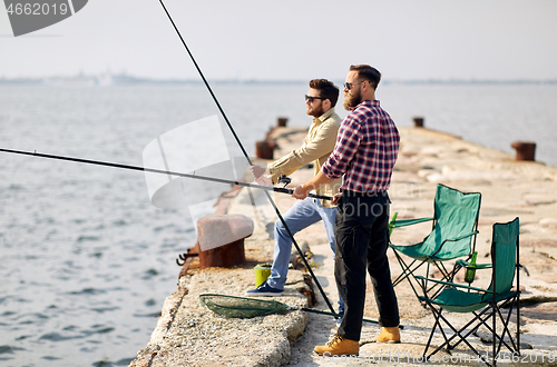 Image of happy friends with fishing rods on pier