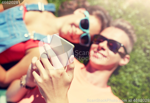 Image of happy teenage couple smartphone lying on grass
