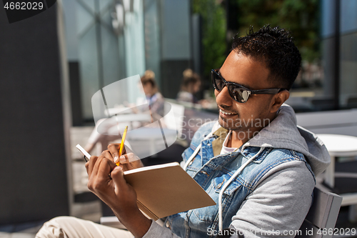 Image of man with notebook and coffee at street cafe