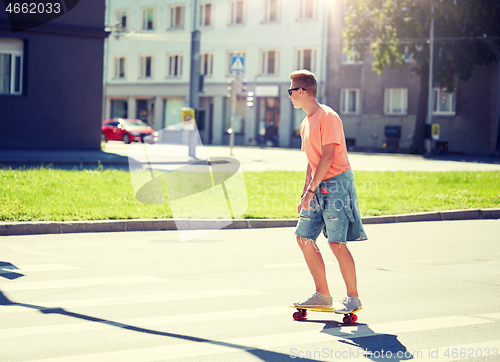 Image of teenage boy on skateboard crossing city crosswalk