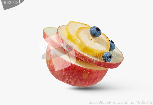 Image of Fresh ripe natural apple with slices of banana and blueberries on a white background.
