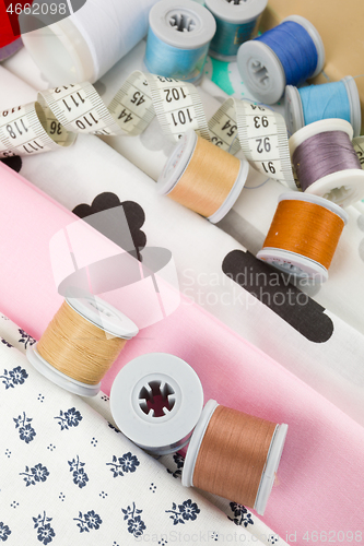 Image of fabric, tailor measurement tape and thread spools
