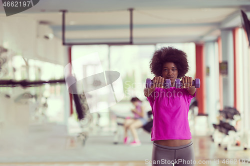 Image of woman working out in a crossfit gym with dumbbells