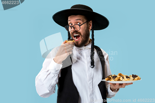 Image of The young orthodox Jewish man with black hat with Hamantaschen cookies for Jewish festival of Purim