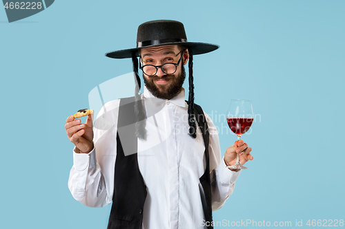 Image of The young orthodox Jewish man with black hat with Hamantaschen cookies for Jewish festival of Purim