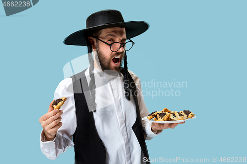 Image of The young orthodox Jewish man with black hat with Hamantaschen cookies for Jewish festival of Purim