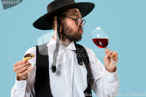 Image of The young orthodox Jewish man with black hat with Hamantaschen cookies for Jewish festival of Purim