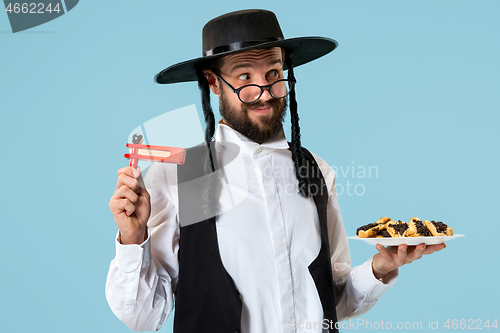 Image of The young orthodox Jewish man with black hat with Hamantaschen cookies for Jewish festival of Purim