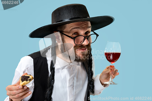 Image of The young orthodox Jewish man with black hat with Hamantaschen cookies for Jewish festival of Purim