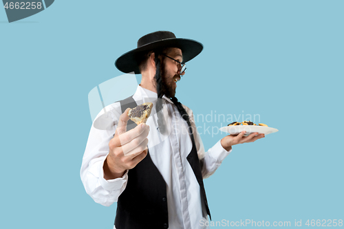 Image of The young orthodox Jewish man with black hat with Hamantaschen cookies for Jewish festival of Purim