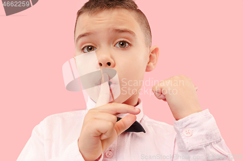 Image of The teen boy whispering a secret behind her hand over pink background