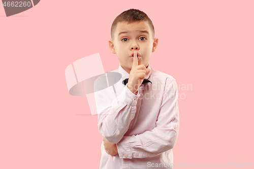 Image of The teen boy whispering a secret behind her hand over pink background