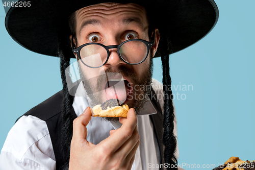 Image of The young orthodox Jewish man with black hat with Hamantaschen cookies for Jewish festival of Purim