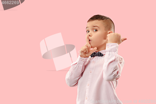 Image of The teen boy whispering a secret behind her hand over pink background