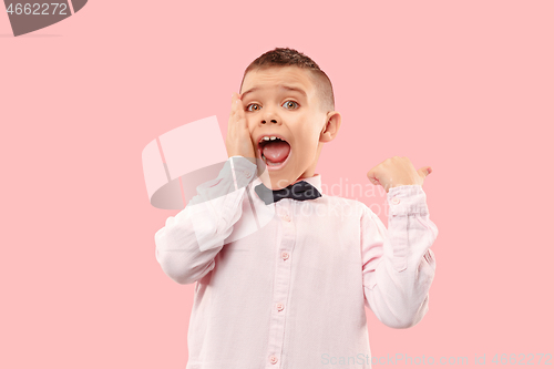 Image of The young attractive teen boy looking suprised isolated on pink