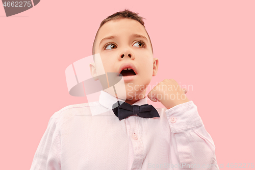 Image of The young attractive teen boy looking suprised isolated on pink